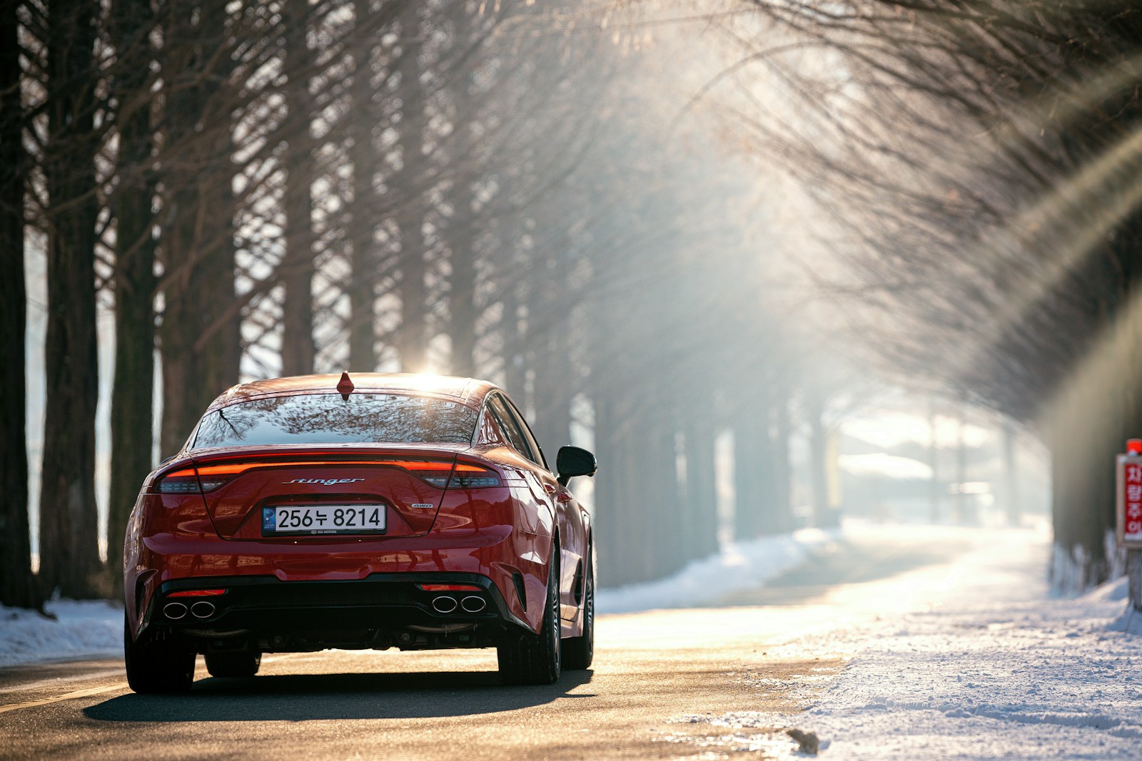 auto insurance a red car driving on a road with snow on the side