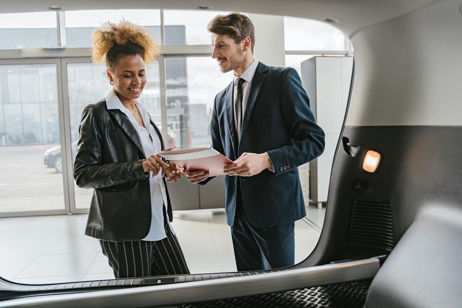 Dealer discussing vehicle options with a client inside a modern car showroom, auto agent